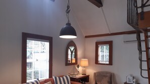 Un salon avec un canapé marron, des coussins à rayures, une table basse en bois, une lampe et une plante en pot.