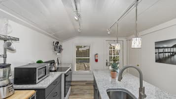 A modern kitchen with granite countertops, stainless steel appliances, and a large window.