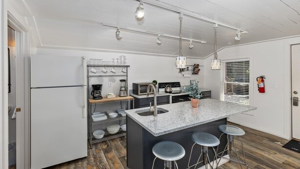 Una cocina compacta con una isla central, taburetes de bar y un horno empotrado.