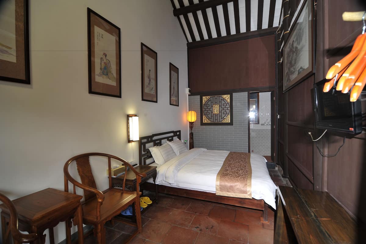 Une chambre traditionnelle avec un lit, des meubles en bois et des œuvres d’art accrochées aux murs.