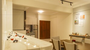 A modern kitchen with a marble island, wooden cabinets, and a dining area with chairs and a table. - Panoramic 180 Cozy Suite by D Imperio Homestay (George Town)