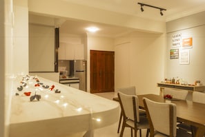 A modern kitchen with a marble island, wooden cabinets, and a dining area with chairs and a table.