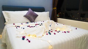 A neatly made bed with white bedding, a purple pillow, and scattered flower petals. - Panoramic 180 Cozy Suite by D Imperio Homestay (George Town)