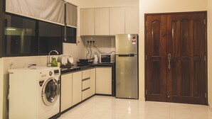 A compact kitchen with a washing machine, microwave, and refrigerator. - Panoramic 180 Cozy Suite by D Imperio Homestay (George Town)