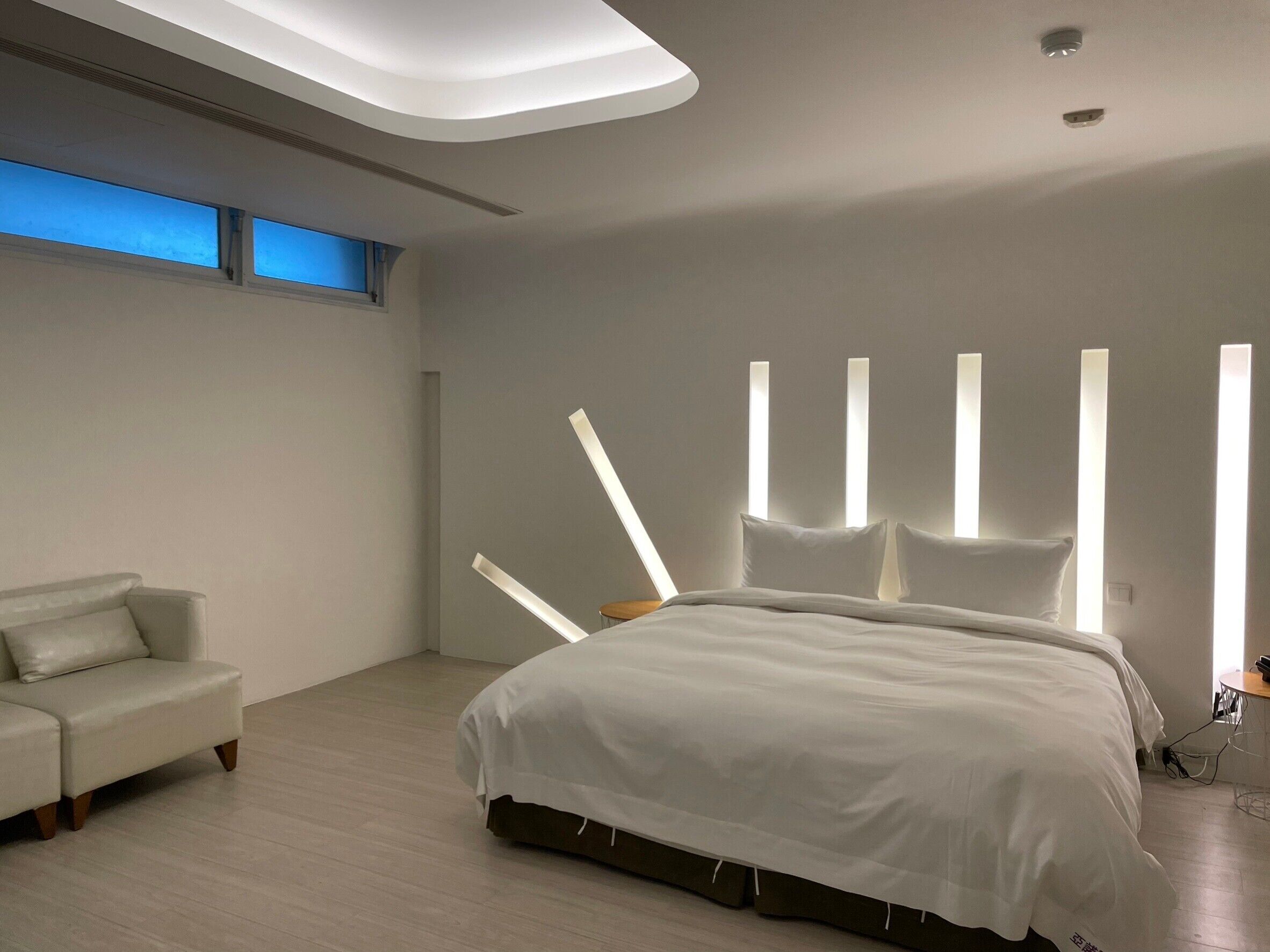 A modern bedroom with a large bed, a sofa, and a skylight.