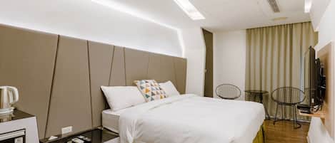 A modern hotel room with a bed, bedside tables, a desk, and a TV.
