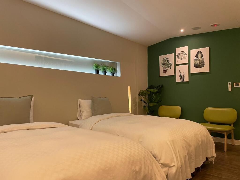 Habitación de hotel con dos camas, una pared verde y obras de arte.