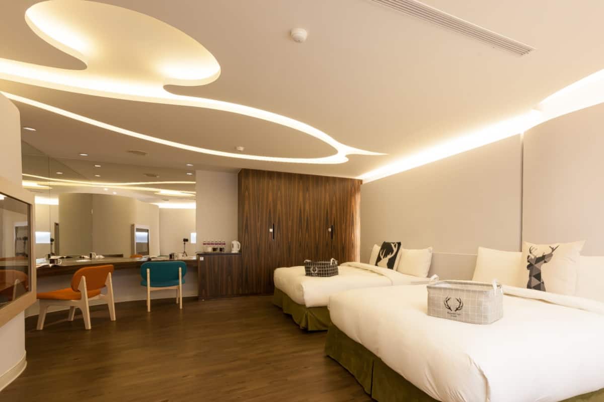 A modern hotel room with a large bed, a desk, and a mirror.