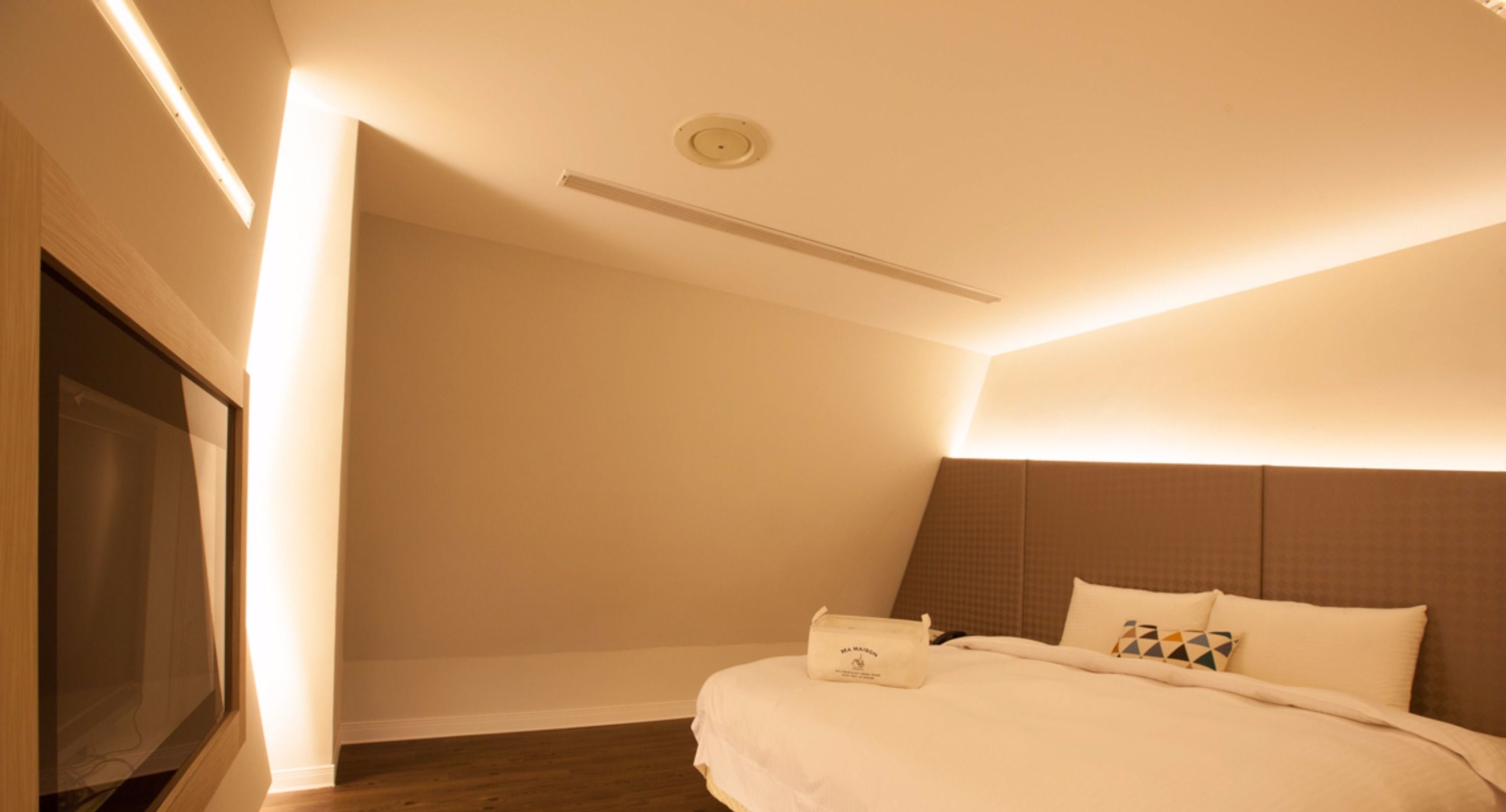 Una habitación de hotel con una cama, un televisor de pantalla plana y un foco en el techo.