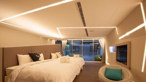 Una habitación de hotel moderna con una cama grande, un espacio para sentarse y vistas al exterior.