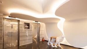 Un interior moderno con un diseño de pared curva, una escultura de oso polar y un ascensor.