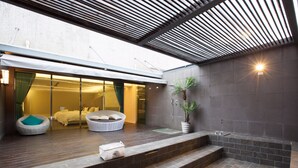 Un baño moderno con pared de baldosas de piedra, un banco de madera y una planta en maceta.