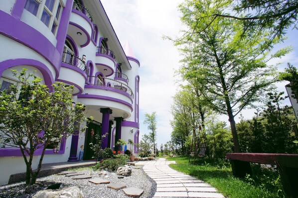 A multi-story building with balconies and a garden pathway.