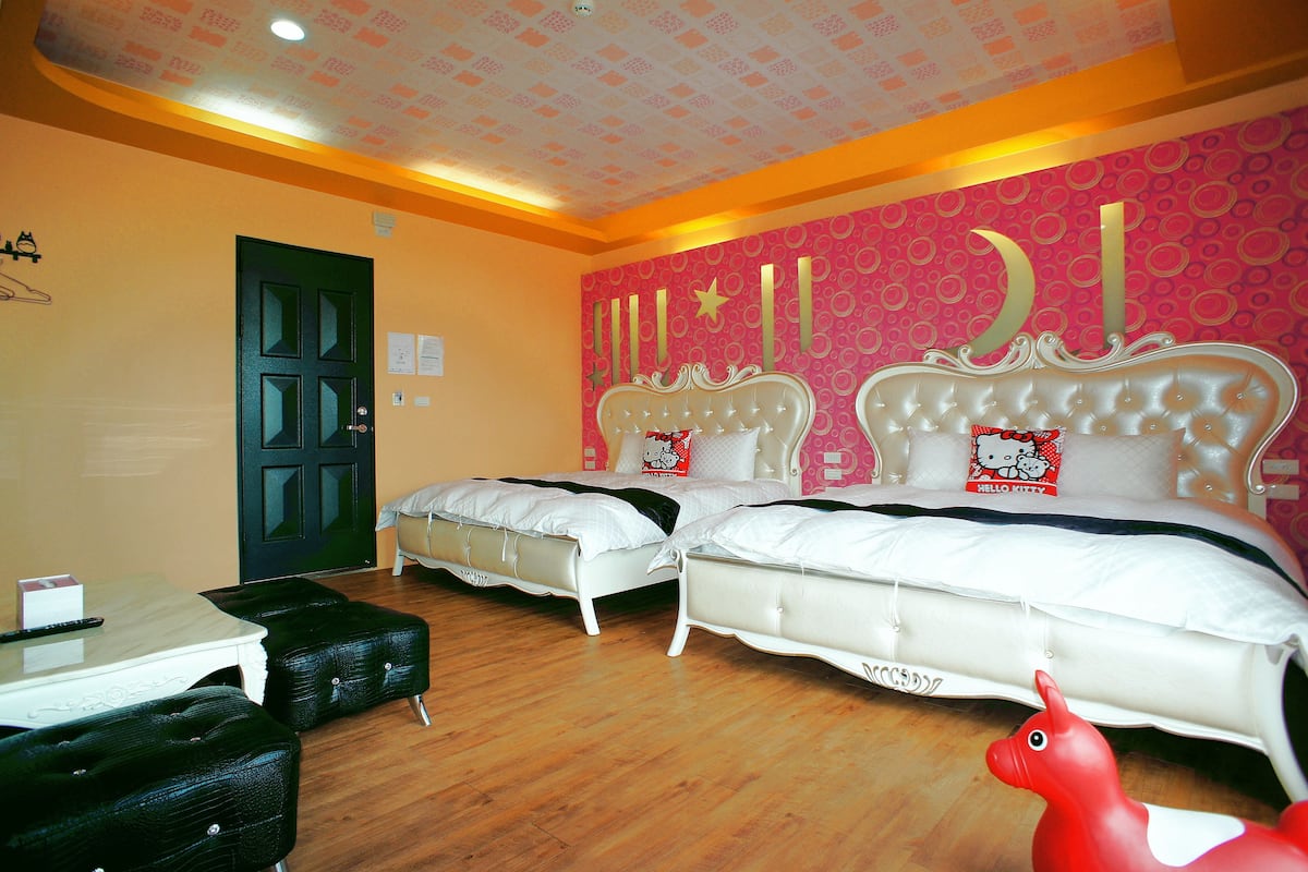 A room with two beds, a table, and a chair.