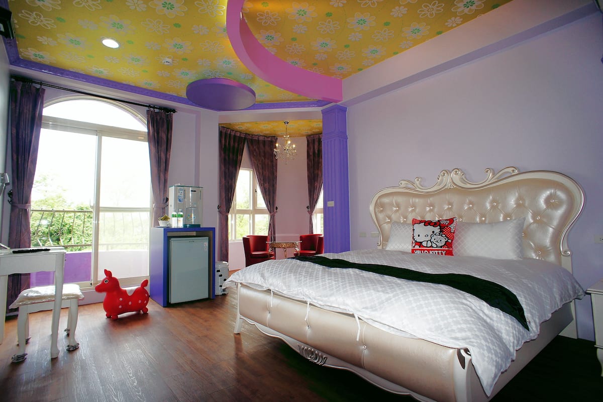 A bedroom with a large bed, a desk, and a chair.
