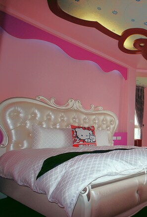 A bedroom with a tufted headboard, a Hello Kitty pillow, and pink walls.