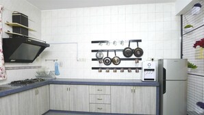 A kitchen with white tiles, a gas stove, a microwave, and a refrigerator. - Bukit Tinggi Klang - Cozy Home (Klang)