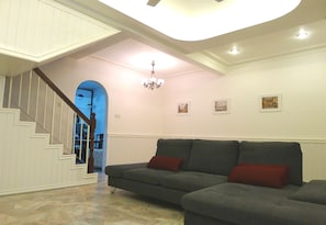 A living room with a grey sectional sofa, a staircase, and a chandelier. - Bukit Tinggi Klang - Cozy Home (Klang)