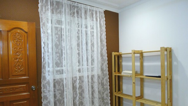 A room with a wooden door, a lace curtain, and a wooden shelf unit against a wall. - Bukit Tinggi Klang - Cozy Home (Klang)