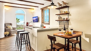 Una cocina con barra, vigas de madera, una lámpara colgante y vistas al exterior a través de un ventanal.