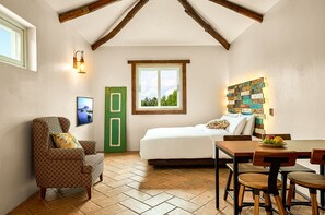 A cozy room with a bed, a dining table with chairs, a green door, and a wall-mounted light fixture. - Sungsan Paradise Hill (Seogwipo)