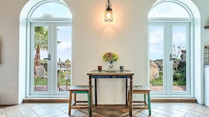 Una habitación con una mesa, dos sillas, un florero y una lámpara de pared.