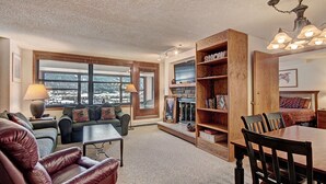 A cozy living room with a fireplace, a large wooden bookshelf, and a dining area with a table and chairs.