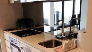 A modern kitchen with stainless steel appliances, a double sink, and a microwave. - Southern Cross CBD Apartment (Melbourne)