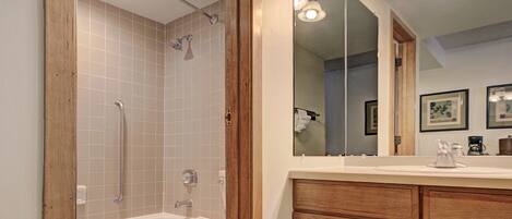 A bathroom with a bathtub, toilet, and a wooden vanity with a mirror.