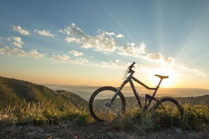 A mountain bike parked on a grassy hill with a sunset in the background. - Newly updated in Canyons Village Next to Slopes by RedAwning (Park City)