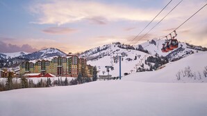 Ein schneebedecktes Bergresort mit Seilbahn, einem mehrstöckigen Hotel und einer Skipiste.