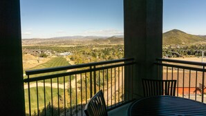 A balcony with a view of a golf course, a mountain, and a residential area.