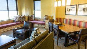 A cozy dining area with a wooden table, cushioned seating, and pendant lighting.