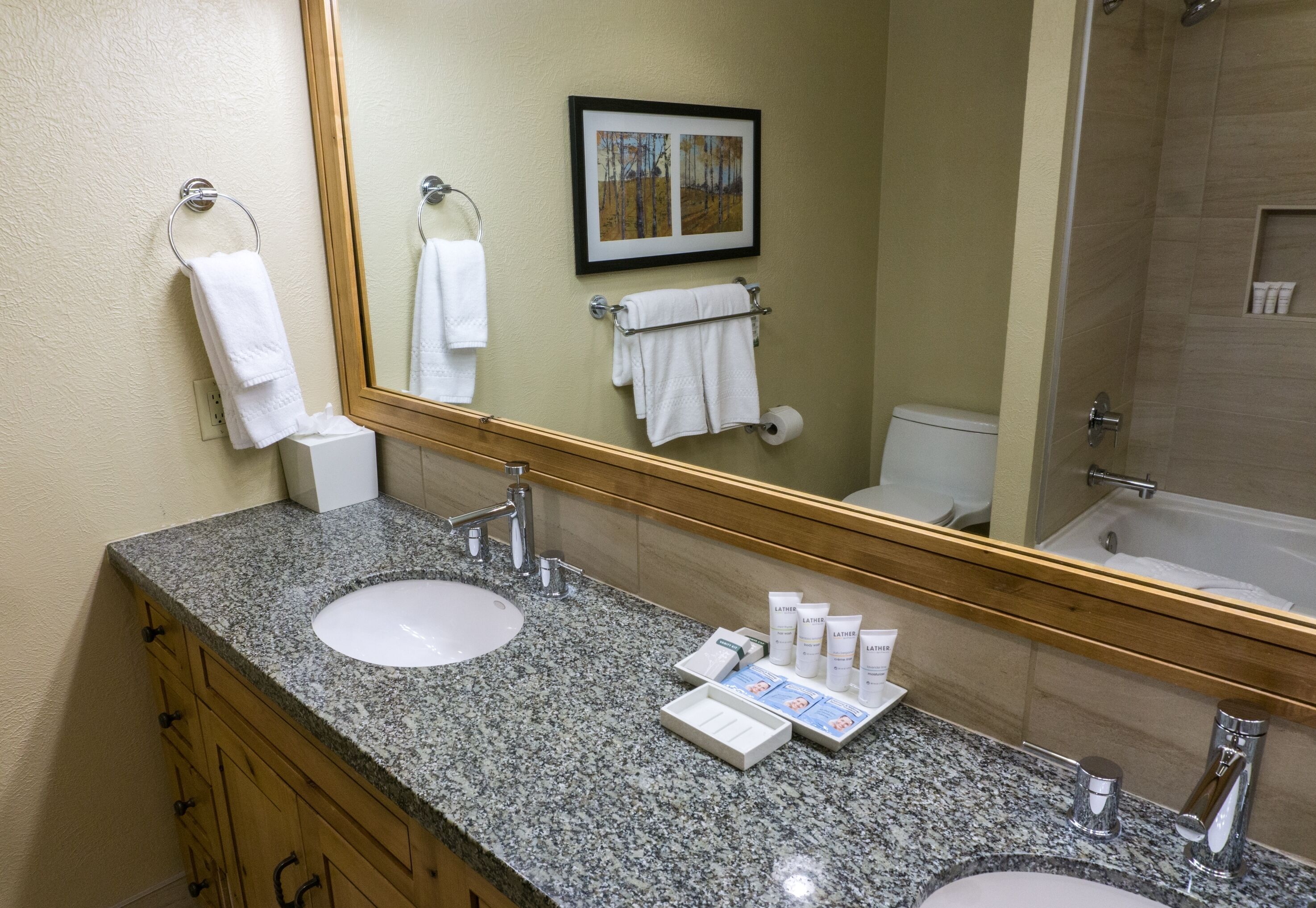 A bathroom with two sinks, a large mirror, and a framed picture on the wall.