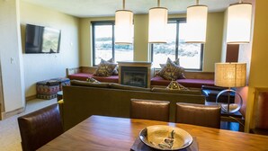 A dining area with a wooden table, cushioned chairs, a fireplace, and a view through large windows. - Exquisite Condo, Great for Families, Ski in/out by RedAwning - Save 20% on 7+ Nights! (Park City)