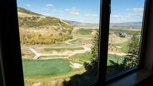 A view of a golf course with a clear sky, distant buildings, and a hilly landscape. - Exquisite Condo, Great for Families, Ski in/out by RedAwning - Save 20% on 7+ Nights! (Park City)