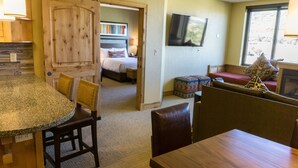A room with a kitchen area, a dining table, a sofa, a bed, and a television. - Exquisite Condo, Great for Families, Ski in/out by RedAwning - Save 20% on 7+ Nights! (Park City)