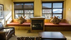 A cozy living room with a fireplace, large windows, and a comfortable seating area. - Rustice Conod with Modern Kitchen  Facilities by RedAwning (Park City)