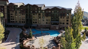 A multi-story hotel with a central courtyard featuring a swimming pool, outdoor seating, and landscaped areas. - Rustice Conod with Modern Kitchen  Facilities by RedAwning (Park City)
