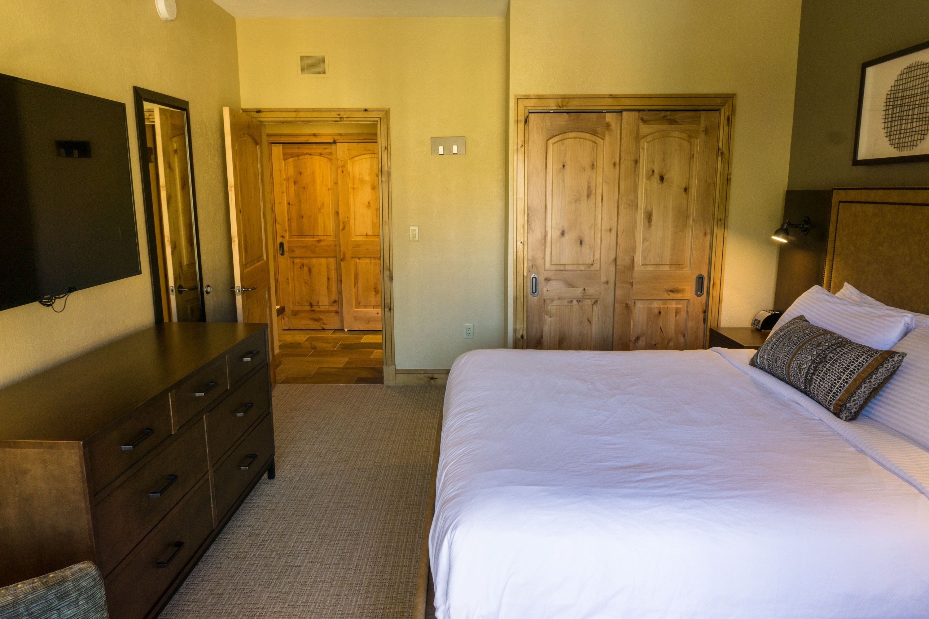 Une chambre à coucher avec un lit, une commode et deux portes en bois.