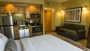 A hotel room with a bed, a sofa, a kitchenette with a refrigerator, microwave, stove, and coffee maker. - Grand Summit views and location, next to slopes by RedAwning (Park City)
