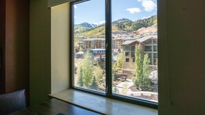A room with a large window overlooking a mountainous area with buildings and trees. - Grand Summit views and location, next to slopes by RedAwning (Park City)