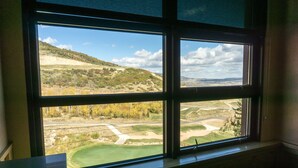 Huone, jossa on suuri ikkuna, josta avautuu näkymä golfkentälle ja kumpuilevaan maisemaan.