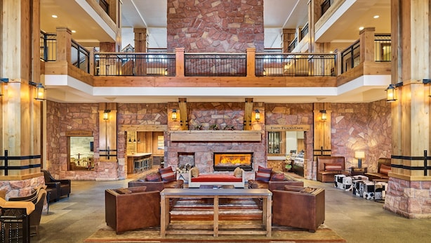 A spacious lobby with a stone fireplace, wooden furniture, and a second-floor balcony.