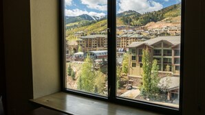 A room with a large window overlooking a mountainous area with buildings.
