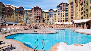 A resort with a central swimming pool, multiple balconies, and outdoor seating areas.