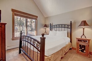 A bedroom with a bed, two bedside lamps, a wooden nightstand, and a window with blinds. - Premier 2-story Townhome Minutes From Winter Activities 3 Bedroom Townhouse by RedAwning (Breckenridge)