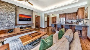 A spacious living room with a stone fireplace, a large flat-screen TV, and a cozy seating area. - 2 Br 2 Ba Luxury Condo. Walk to South Lake Tahoe! (South Lake Tahoe)