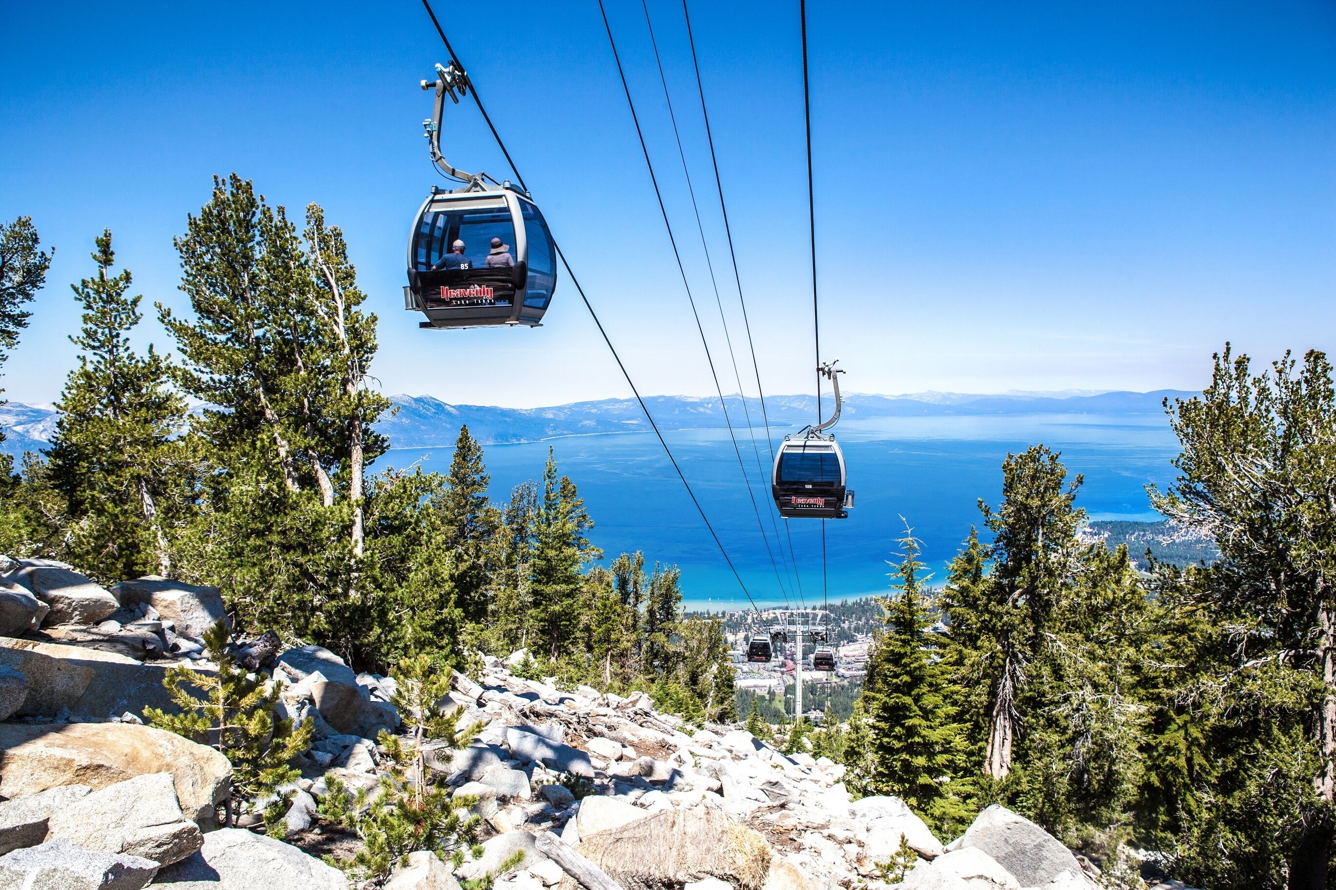 Teleférico com vista desobstruída de uma paisagem montanhosa e um corpo d'água ao longe.