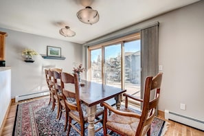 A dining area with a wooden table and chairs, a large window with a view of a snowy landscape, and a ceiling fan. - Streamside 333B (Frisco)